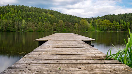 Footbridge on a lake with clouds on the sky in the bavarian forestの写真素材
