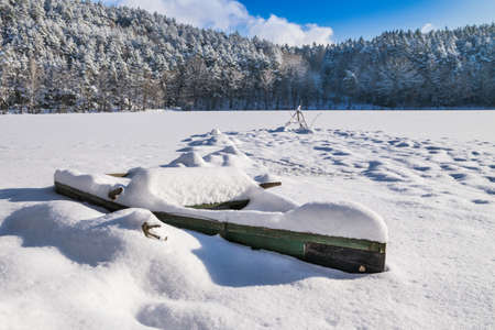 Wooden boat on the frozen lake in the bavarian forestの写真素材