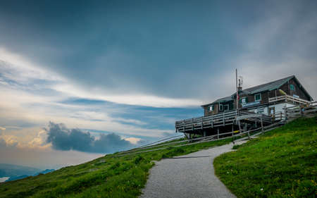 House on top of a mountain with clouds and sunset on the backgroundの写真素材