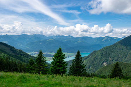 View from top of a mountain in the valley and clouds and mountains in the background in austriaの写真素材