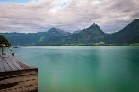 Footbridge at the Wolfgangsee in Austria with mountains in the background and clouds on the skyの写真素材