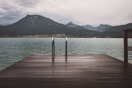 Footbridge at the Wolfgangsee in Austria with mountains in the background and clouds on the skyの写真素材