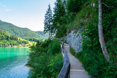Jetty on the edge of the turquoise lake called Wolfgangsee mountains in the background and clouds on...