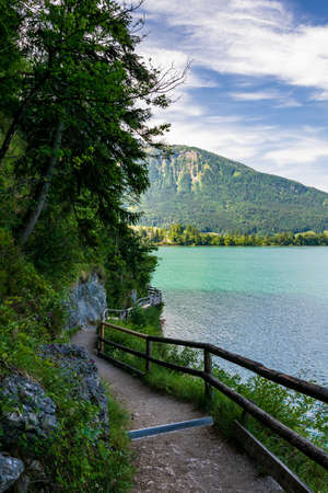 Jetty on the edge of the turquoise lake called Wolfgangsee mountains in the background and clouds on the skyの写真素材