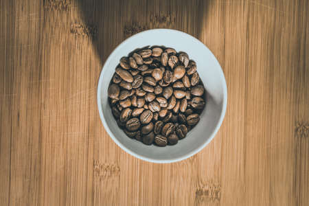 Cup of Coffee Beans roasted on a wooden table with fresh bean with great aromaの写真素材