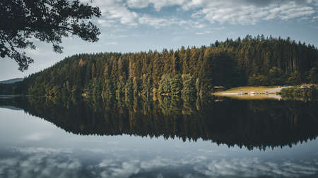 Lake with Reflection on the Water and Trees in the background and Clouds on the sky in the bavarian forestの写真素材