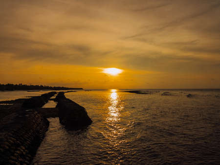 Sunset in the Maldives with reflection of the Sun in the water and blue and orange colored clouds in the skyの写真素材