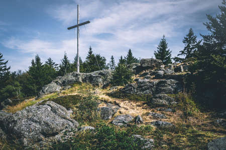 View from the top of a mountain into the valley with clouds in the blue sky and beautiful green trees and lots of rocksの写真素材