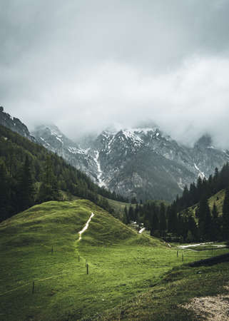 View of the mountains in Berchtesgaden on the Koenigssee with clouds in the sky and stones and rocks in the foregroundの写真素材