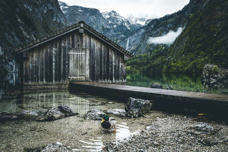 Boathouse at the Obersee in the bavarian alps with mountains in the background and clouds on the sky near Berchtesgadenの写真素材