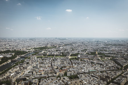 A panoramic aerial view of Paris featuring the Seine River winding through the city, modern buildings, bridges, and urban greenery. The image captures a mix of contemporary and classic Parisian architecture under a bright blue sky. Ideal for travel, cityscape, and architectural themesの写真素材