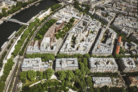 A panoramic aerial view of Paris featuring the Seine River winding through the city, modern buildings, bridges, and urban greenery. The image captures a mix of contemporary and classic Parisian architecture under a bright blue sky. Ideal for travel, cityscape, and architectural themes.の写真素材
