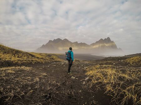 Man standing in front of spiky mountains. The Vikings Village in Höfn in Eastern Region of Iceland...