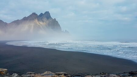 Tall mountains emerging from a sea. Slight reflections of the mountains in a shallow sea shore....