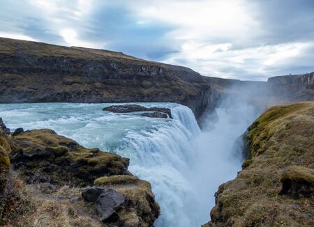 A mighty waterfall, falling into a gorge, spreading on a vast distance. Bottom of the waterfall is not visible. Gullfoss waterfall located in the canyon of the HvÃ­tÃ¡ river in southwest Icelandの写真素材