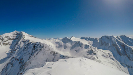 A beautiful and serene landscape of mountains covered with snow. Thick snow covers the slopes. Clear weather. Sharp slopes of the mountains covered with snow, with partially visible rocks.の写真素材