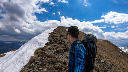 A man taking a selfie while walking on the slopes of Himmeleck in Austrian Alps. There is a massive...