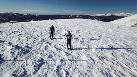A drone shot of a couple wearing snow shoes hiking up to the peak of Speikkogel in Austrian Alps....