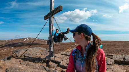 A couple playing under a wooden cross on top of Sauofen in Austrian Alps. They are happy because...