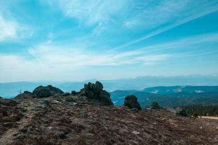 Vast, golden pasture on top of Sauofen, Austrian Alps. A lot of big stones on the grounds. High mountain chains in the back. There is a cross on a distant peak. Outdoor activity. Serenity and calmnessの写真素材