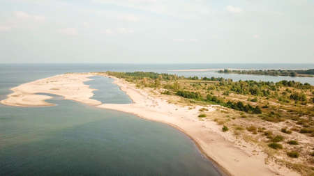 A areal shot of on Vistula Przekop - an area where Vistula river is merging with Baltic Sea on Sobieszewo island, Poland. The sea's side is sandy, the river's side is overgrown with trees.の写真素材