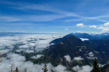 A panoramic view from the top of Alpine peak in Austria. The whole area is shrouded in thick clouds. A few peaks popping out from the clouds. High mountain chains in the back. Carpet from the cloudsの写真素材
