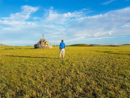 A man standing on a vast pasture in Xilinhot in Inner Mongolia, and admiring a heap of stones...