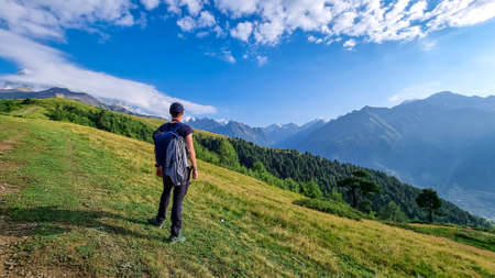 A male hiker enjoying the amazing views on the mountain ridges in the Greater Caucasus Mountain Range in Georgia, Samegrelo-Upper Svaneti Region. Alpine pasture along the path.Wanderlust.Koruldi Lakesの写真素材