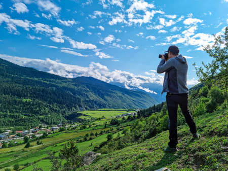 A male photoprapher enjoying the amazing view on the valley in Mestia in the Greater Caucasus...