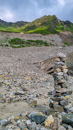 Stacked stones in front of the Shkhara Glacier in the Greater Caucasus Mountain Range in Georgia,...