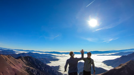 A happy couple full of joy reaching the summit of Eisenerzer Reichenstein in Styria,Austria,Europe. Ennstal valley is covered in clouds.Hiking trail,Wanderlust. Sunny day.Freedom achievement conceptの写真素材