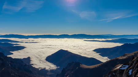 A panoramic view from mount Eisenerzer Reichenstein (2165m) near Eisenerz in Styria, Austria, Europe. Austrian Alps. The Ennstal valley is covered in clouds and fog. Hiking trail,Wanderlust. Sunny dayの写真素材