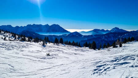 Panoramic view on snow capped mountain peaks of Karawanks in Carinthia, Austria. Julian Alps. Winter wonderland in the Austrian Alps, Europe. Ski tour, snow shoe hiking. Hochobir. Blue misty hills.の写真素材