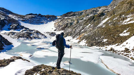 Hiking man with backpack with scenic view on the High Tauern mountains in Carinthia, Salzburg, Austria, Europe, Alps. Glacier lakes of Goldbergkees in Hohe Tauern National Park. Patagonia landscapeの写真素材