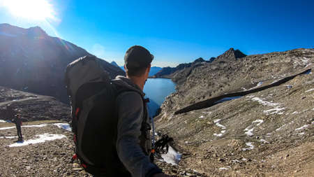Man with big backpack hiking with a scenic view on the mountains of Hohe Tauern Alps in Carinthia, Austria, Europe. A lake and water reservoir in the moelltaler glacier. Hohe Tauern National Park.の写真素材