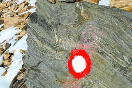 Circular red and white path mark on a layered rock in the Hohe Tauern Alps in Carinthia, Austria, Europe. Rock formations in the Hohe Tauern National Park. Hiking trail of the Tauern Hoehenweg. Trekの写真素材