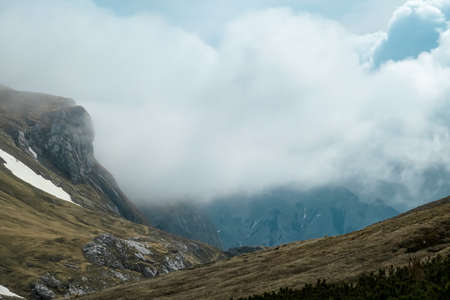 Scenic hiking trail over an alpine meadow in the cloud covered mountain peaks of the Hochschwab...