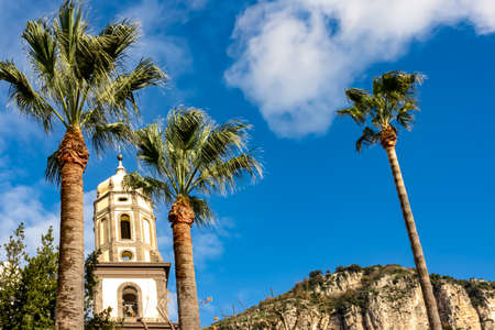 Basilica Pontificia della Madonna del Lauro surrounded by tall palm trees reaching up a blue,...