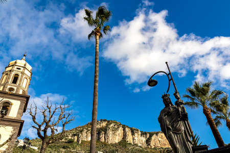 Basilica Pontificia della Madonna del Lauro surrounded by tall palm trees reaching up a blue,...