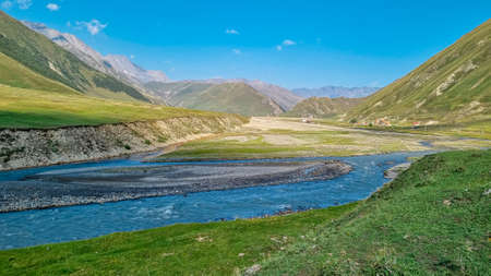 The Terek (Tergi) river flows down the Truso Valley near the Ketrisi Village Kazbegi District,Mtskheta in the Greater Caucasus Mountains,Georgia.Ketrisi village and Zakagori Fortress in the distanceの写真素材