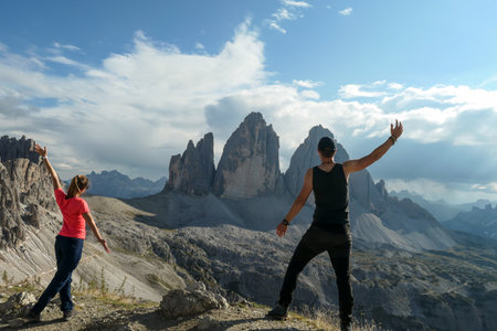 A couple in hiking outfit standing on top of Sextner Stein and enjoying the view on the famous Tre...