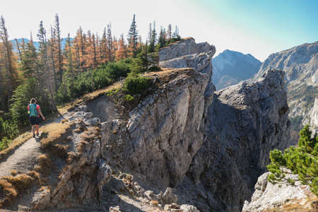 Woman hiking along a very steep and narrow mountain ridge in Hochschwab region in Austrian Alps. Steep fall into the valley. Massive Alps. Autumn vibes in the mountains. Freedom and wildernessの写真素材