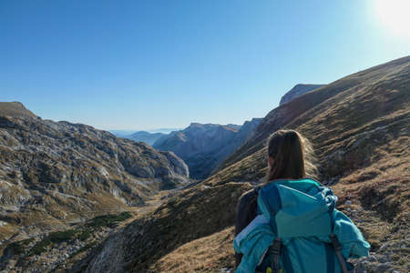 A woman hiking in Hochschwab region in Austrian Alps. Steep mountain chain in front of her. Massive Alps. Autumn vibes in the mountains. Idyllic landscape. Freedom and wildernessの写真素材