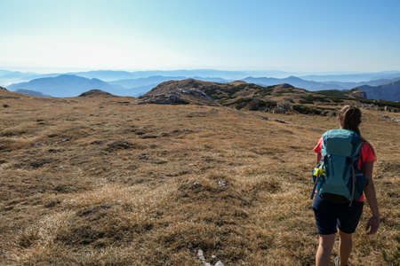 A woman hiking on a meadow in Hochschwab region in Austrian Alps. Endless mountain chains in front...