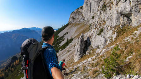 A couple hiking in Hochschwab region in Austrian Alps. The man is taking a selfie. The flora overgrowing slopes is turning golden. Idyllic landscape. Freedom and wilderness. Pathless wanderingの写真素材