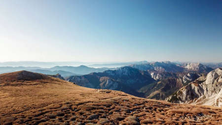 A panoramic view on the plain on top of a mountain in Hochschwab region in Austrian Alps. The flora overgrowing the slopes is turning golden. Autumn vibes. Sharp and steep mountain chain. Wildernessの写真素材
