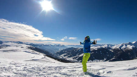 A young man wearing a blue skiing jacket doing yoga at the top of Katschberg, ski resort in Austria. The man spreads open his arms. Yogi's remedy. Solitude and awareness. Winter wonderlandの写真素材