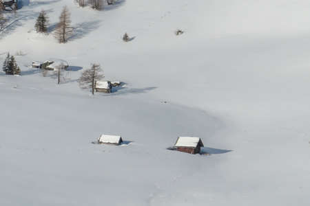 A few mountain cottages covered with a layer of thick snow, located on the slopes of Katschberg Ski...