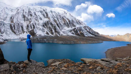 Man standing at the turquoise colored Tilicho lake in Himalayas, Manang region in Nepal. The world's...