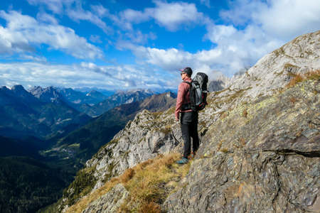 Man reaching the top of Monte Coglians, Hohe Warte on Austrian-Italian Alpine border. Very steep and narrow pathway that he walks on. He is enjoying the landscape. Goal visualization. Stunning viewの写真素材